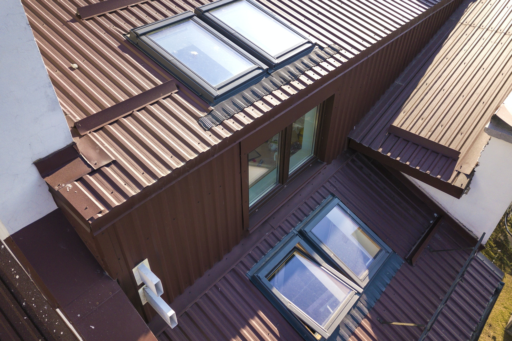 Aerial view of annex room exterior with plastic attic windows, roof and walls covered with brown