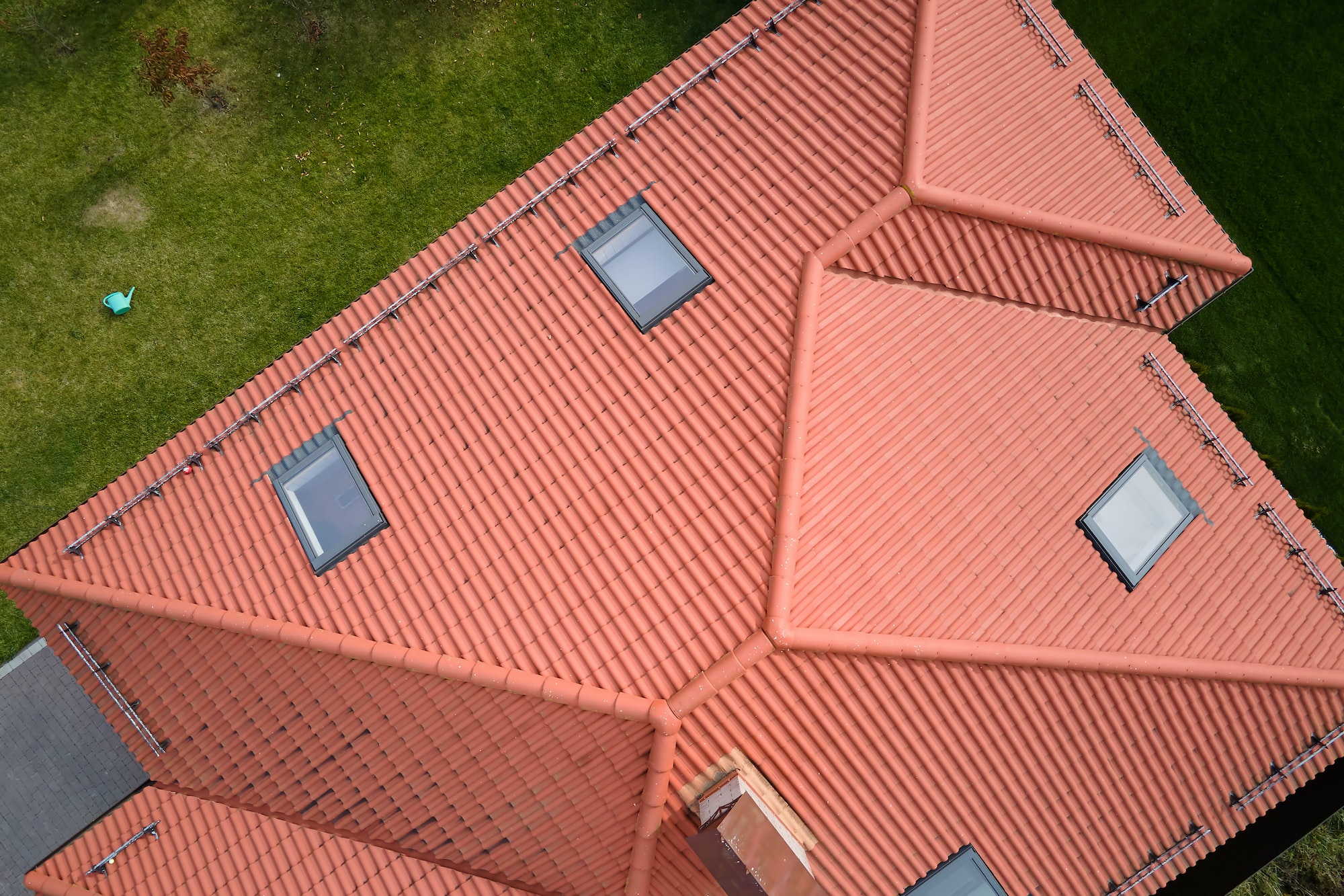 Closeup of attic windows on house roof top covered with ceramic shingles. Tiled covering of building
